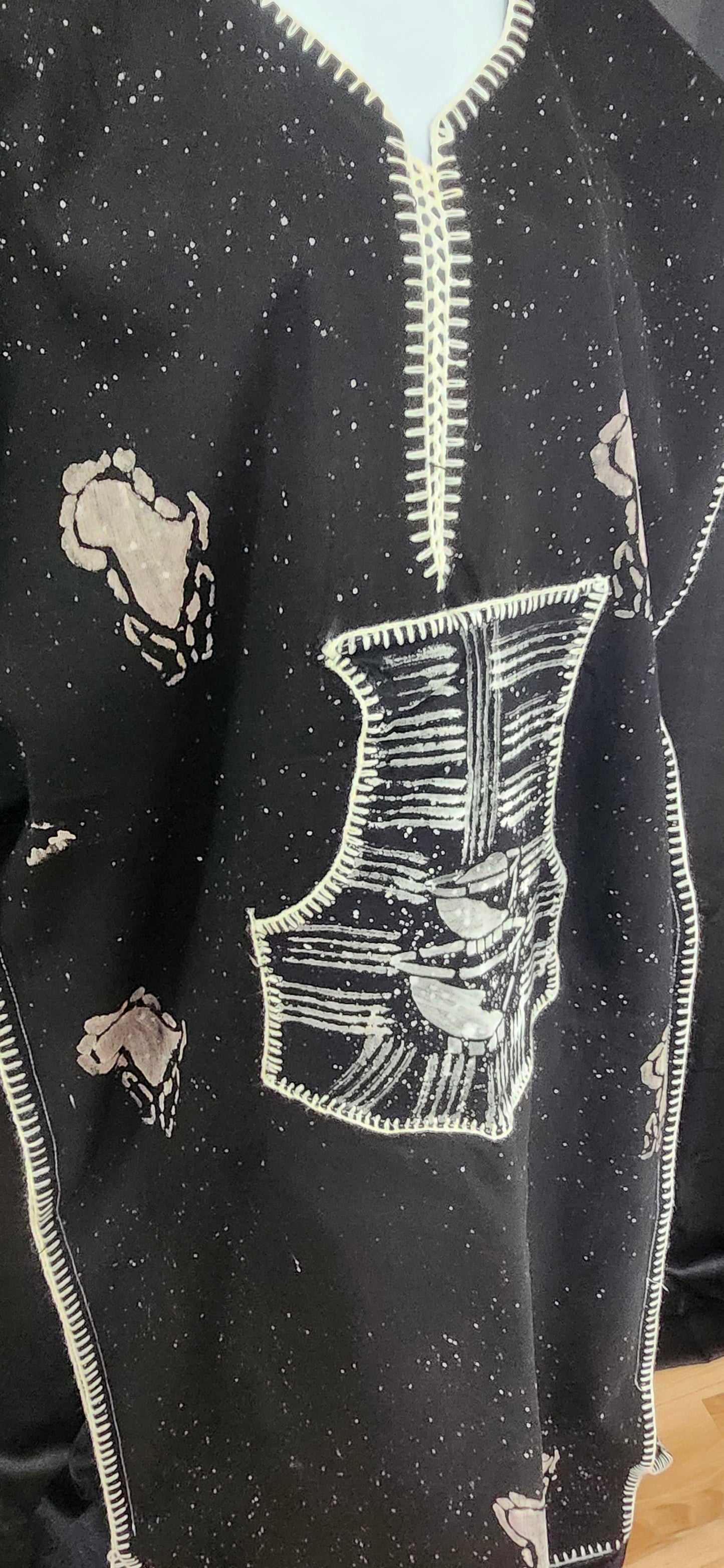 Black fabric with white embroidered patterns on a wooden surface