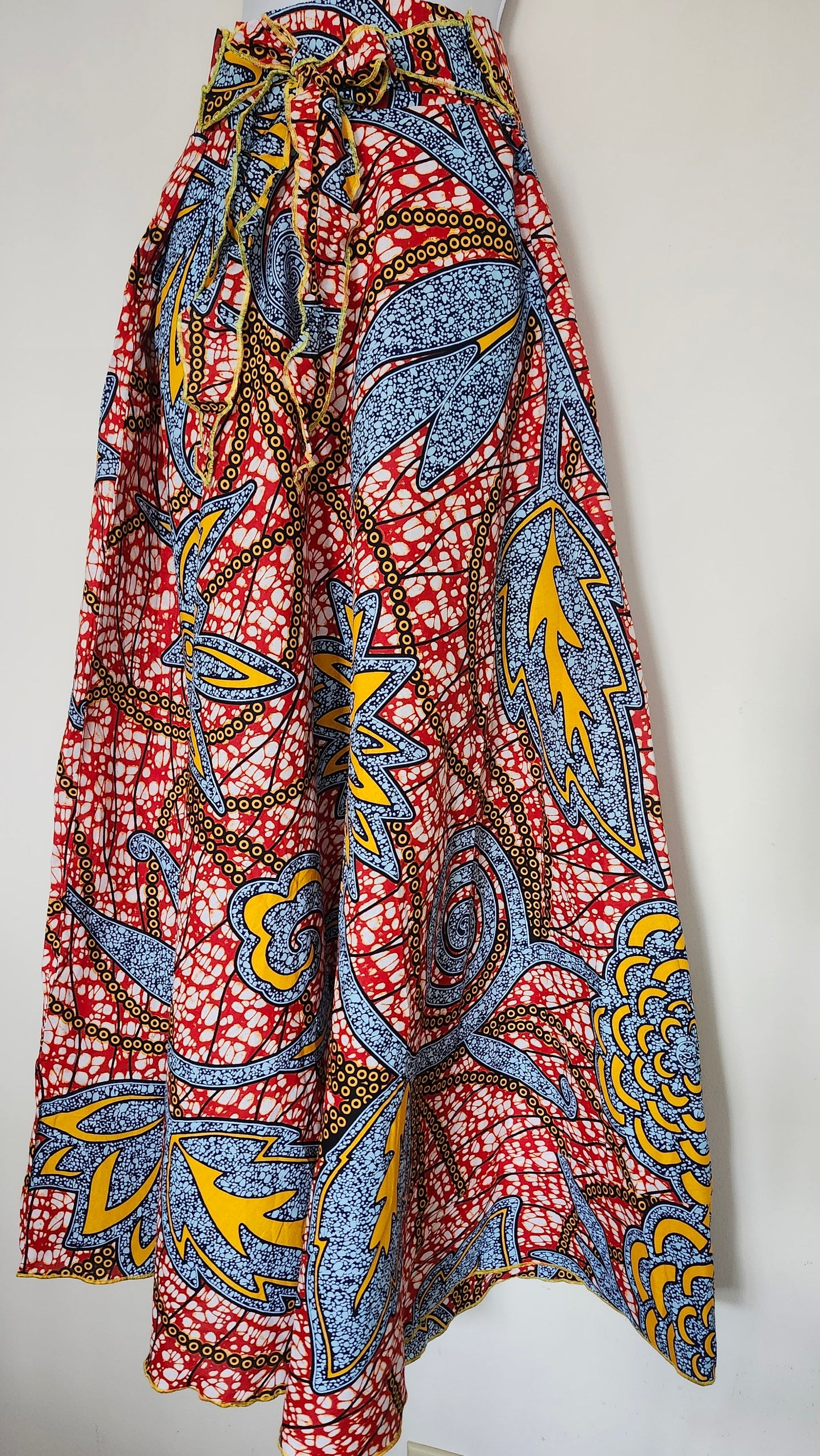 Colorful patterned skirt hanging on a white wall.