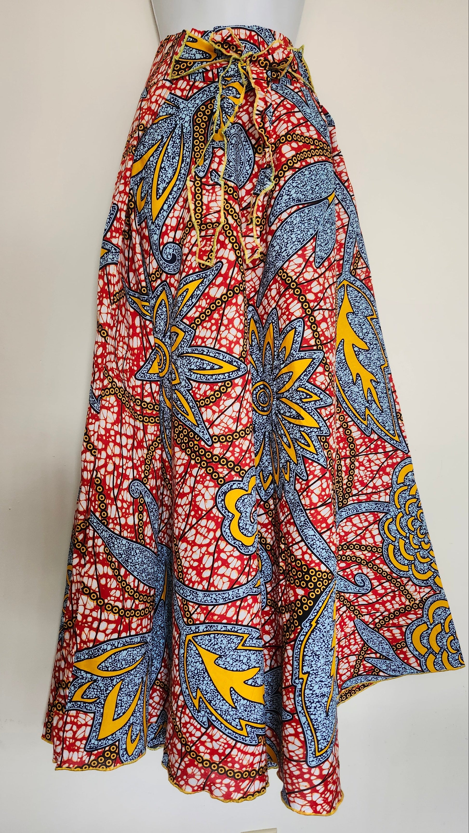 Colorful African print maxi skirt with blue, yellow, red, and white leaf 
patterns, full-length flowy design, displayed against a plain white background