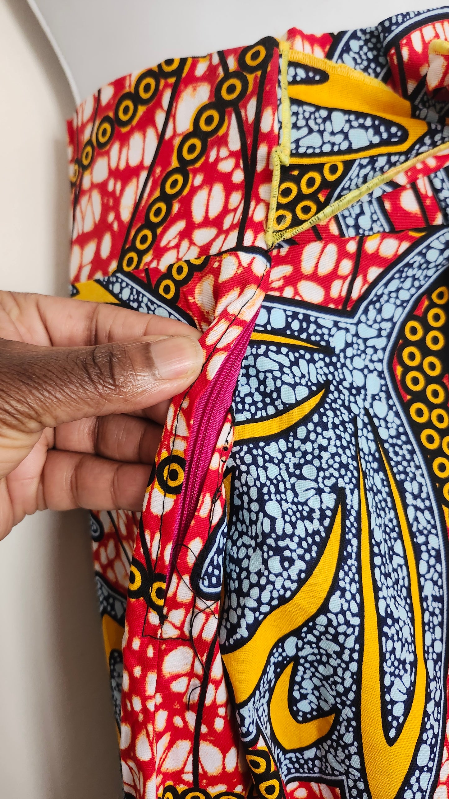 Colorful fabric with intricate patterns held by a hand against a white background