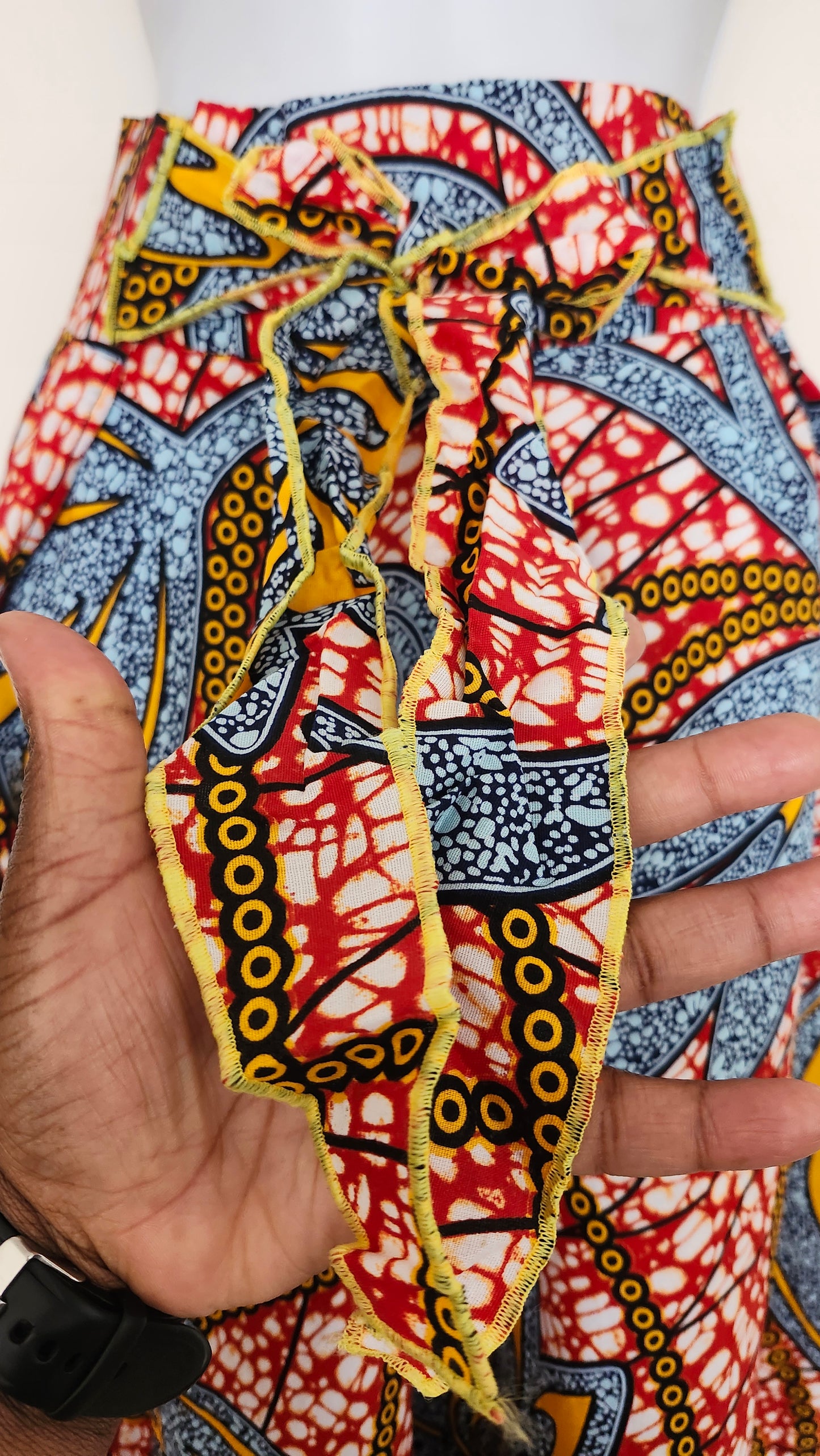 Close-up of a colorful fabric with intricate patterns held by a hand.