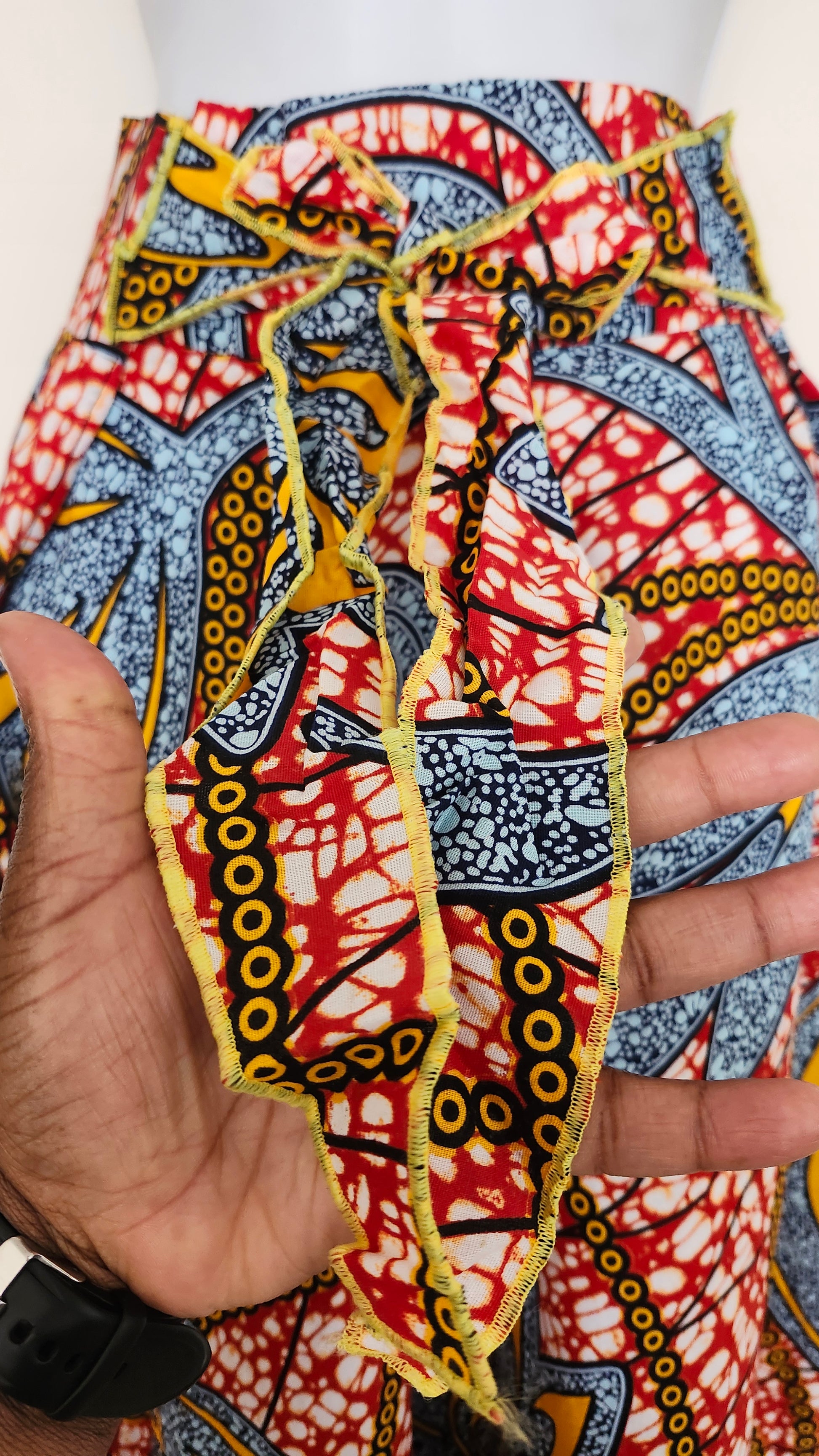 Close-up of a colorful fabric with intricate patterns held by a hand.